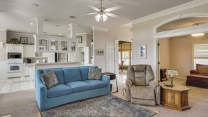 A spacious living room with a blue sofa, a grey armchair, and a patterned rug.