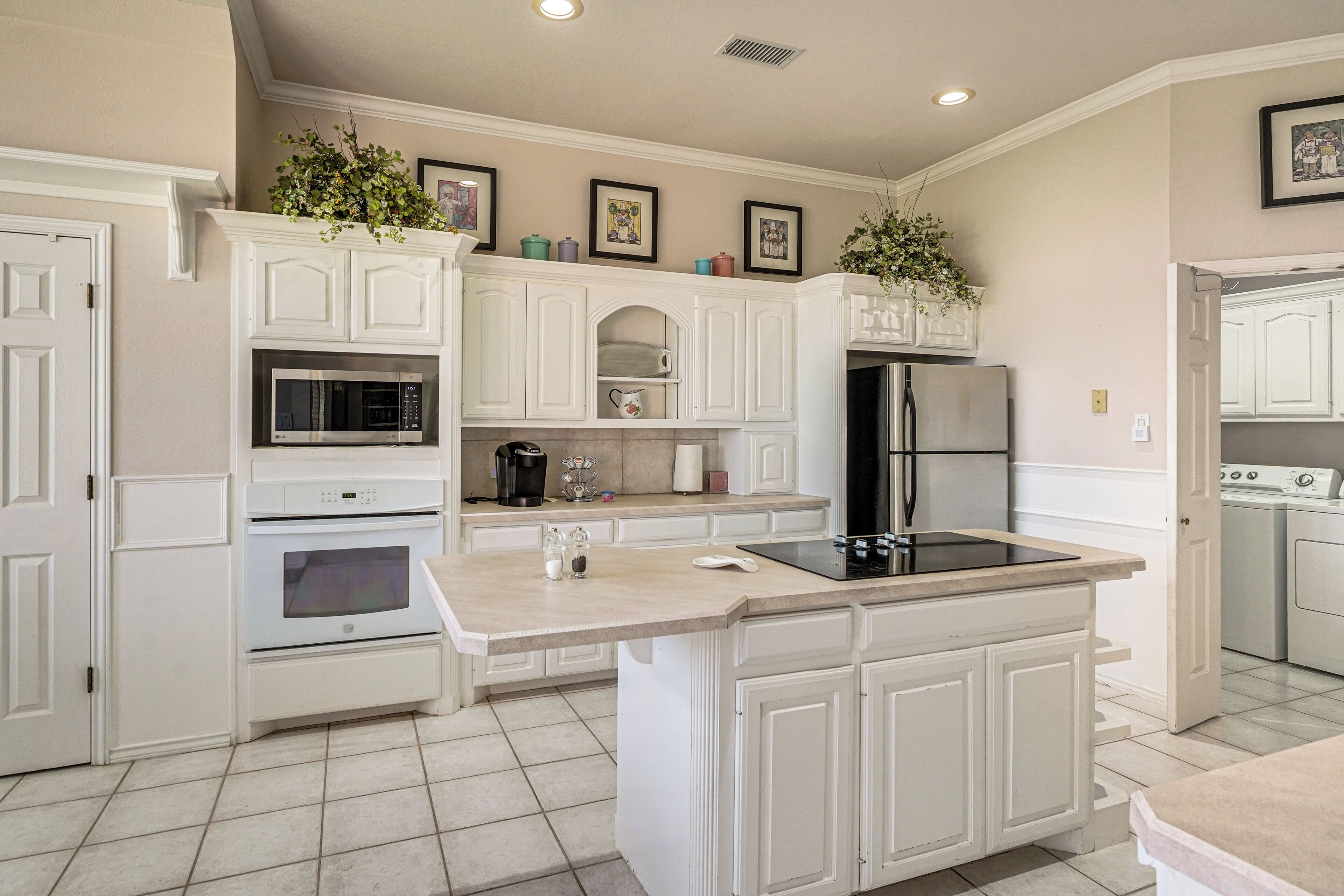 A kitchen with white cabinetry, a built-in microwave, an oven, a refrigerator, and a sink.