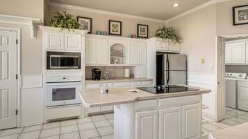 A kitchen with white cabinetry, a built-in microwave, an oven, a refrigerator, and a sink.