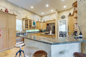 Una cocina amplia con encimeras de granito, electrodomésticos de acero inoxidable y armarios de madera.
