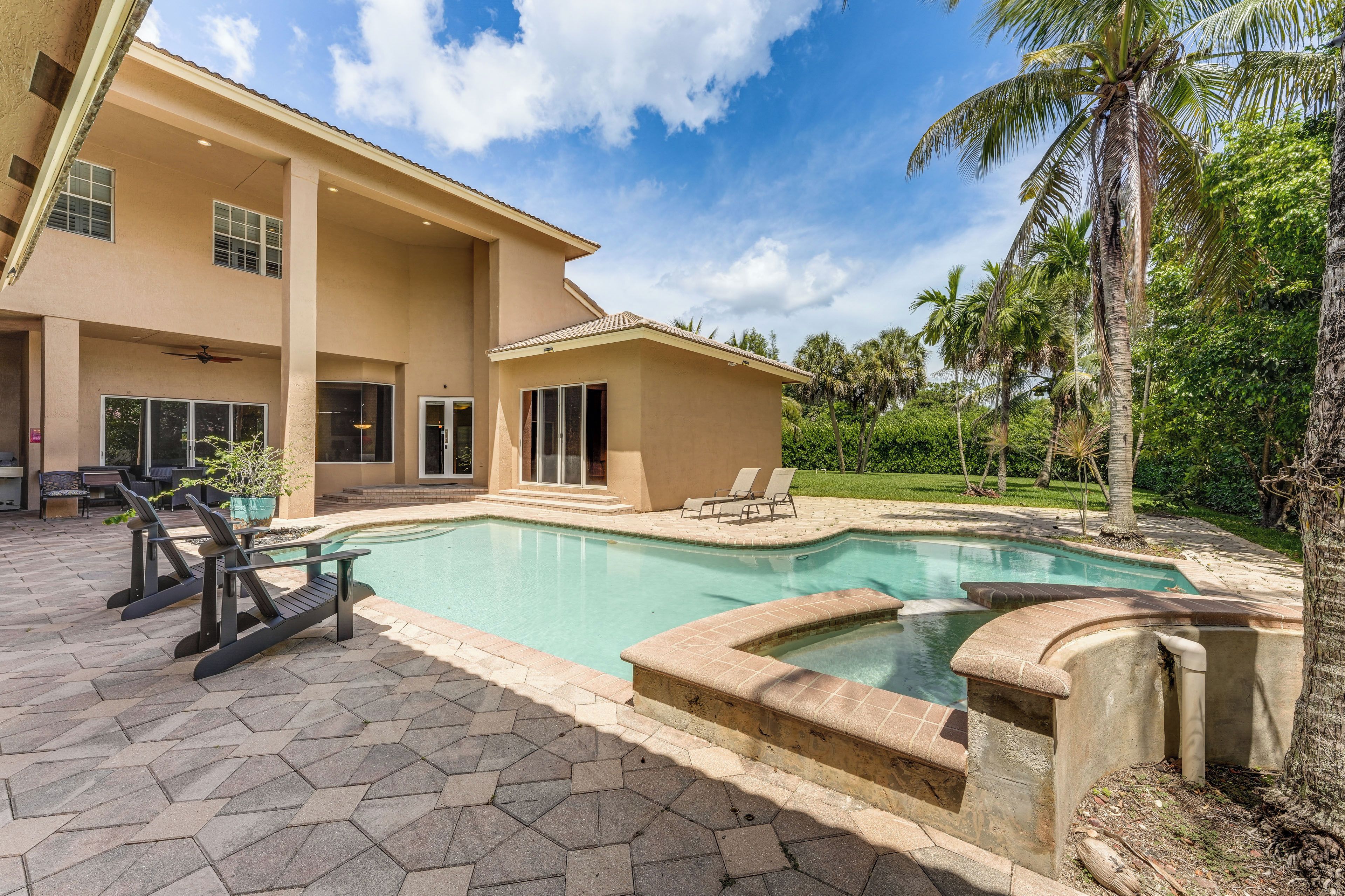 A large house with a swimming pool, outdoor furniture, and a well-maintained garden.