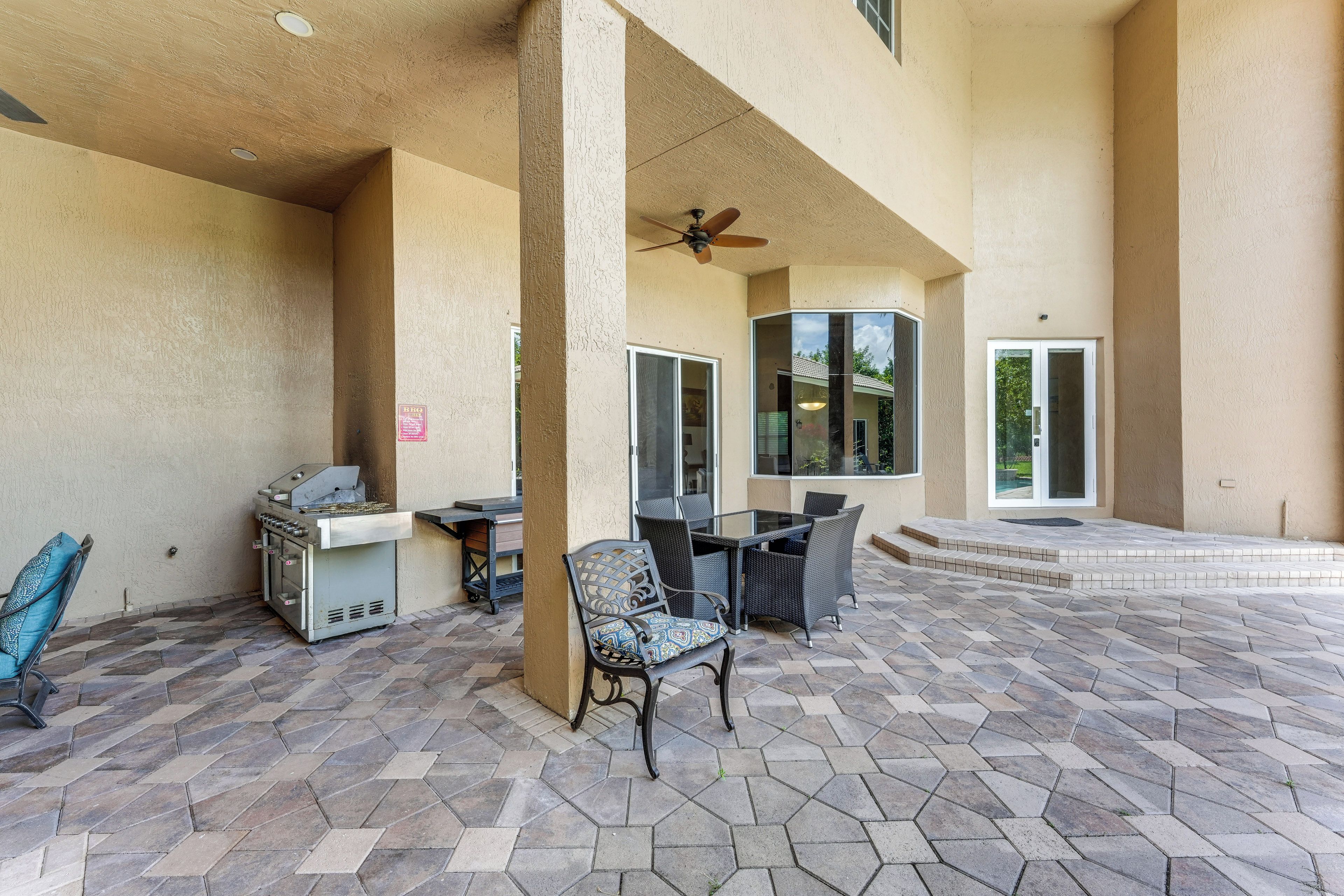 An outdoor patio with a grill, dining table, and chairs.