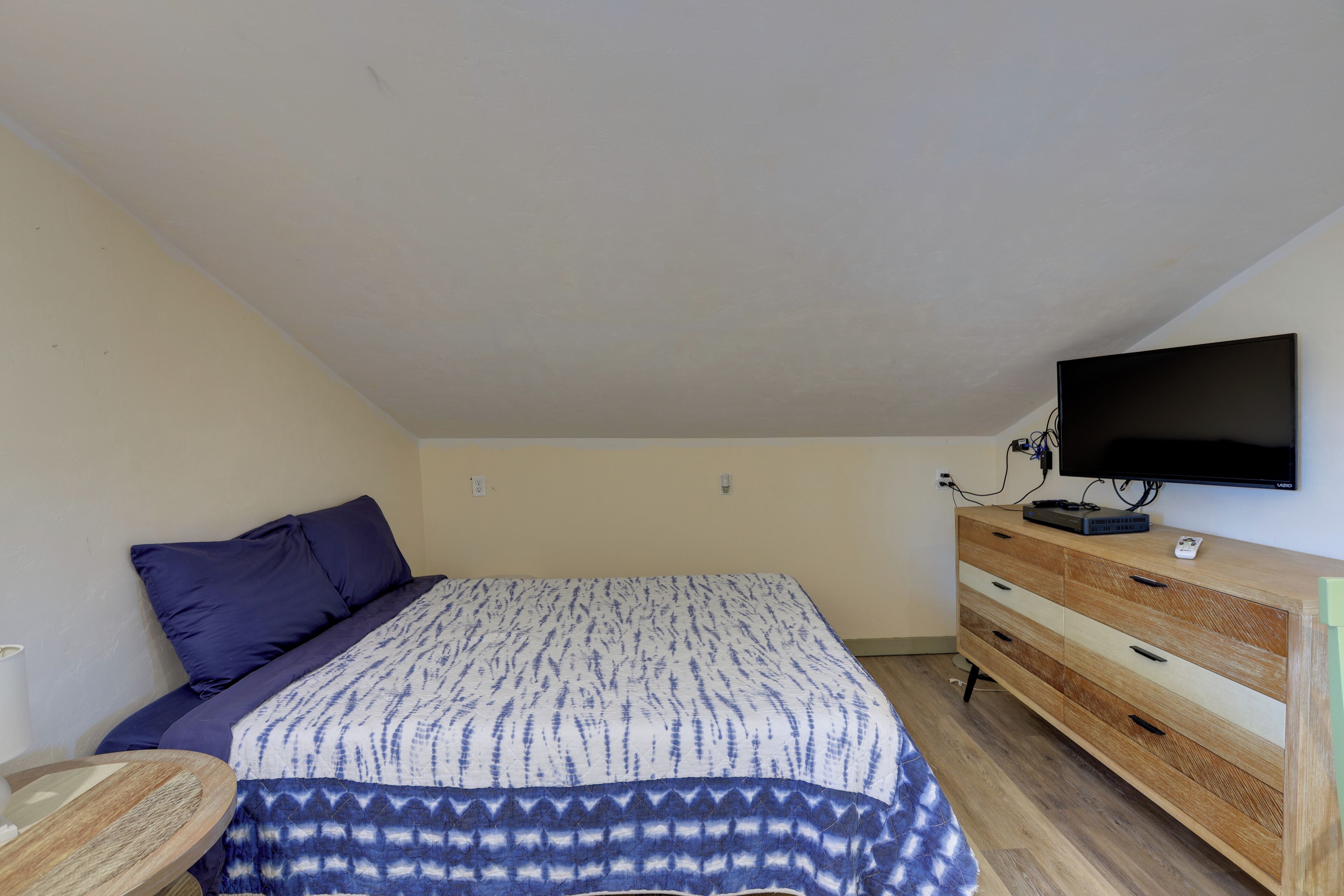 Una camera da letto con un letto, una cassettiera, una televisione e una scrivania.