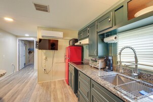 Una cocina con encimera de granito, pileta de acero inoxidable y refrigerador rojo.