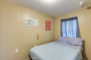 A bedroom with a bed, a window with curtains, a wall-mounted light fixture, and a small wall decoration. - 5-unit Retreat Near World Equestrian Center & Hits (Morriston)