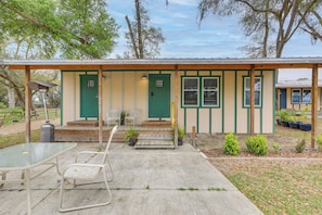 A small building with a green door and windows, a covered patio with a table and chairs, and potted plants. - 5-unit Retreat Near World Equestrian Center & Hits (Morriston)