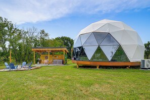A geodesic dome structure with a wooden deck and outdoor seating area.