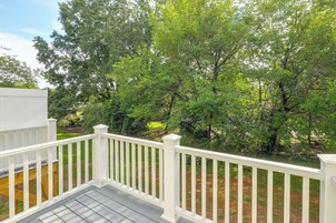 A wooden deck with white railings overlooking a grassy area with trees.