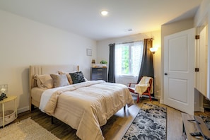 Une chambre à coucher avec un lit, une table de chevet, une lampe, une chaise et une porte.
