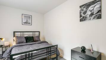 A minimalist bedroom with a bed, bedside table, and a dresser.