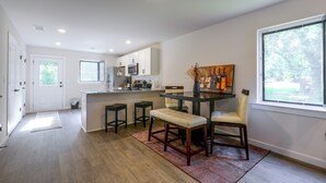 A modern kitchen with a central island, bar stools, and a dining table with chairs. - Hickory Townhome w/ Deck: 2 Mi to Downtown (Hickory)