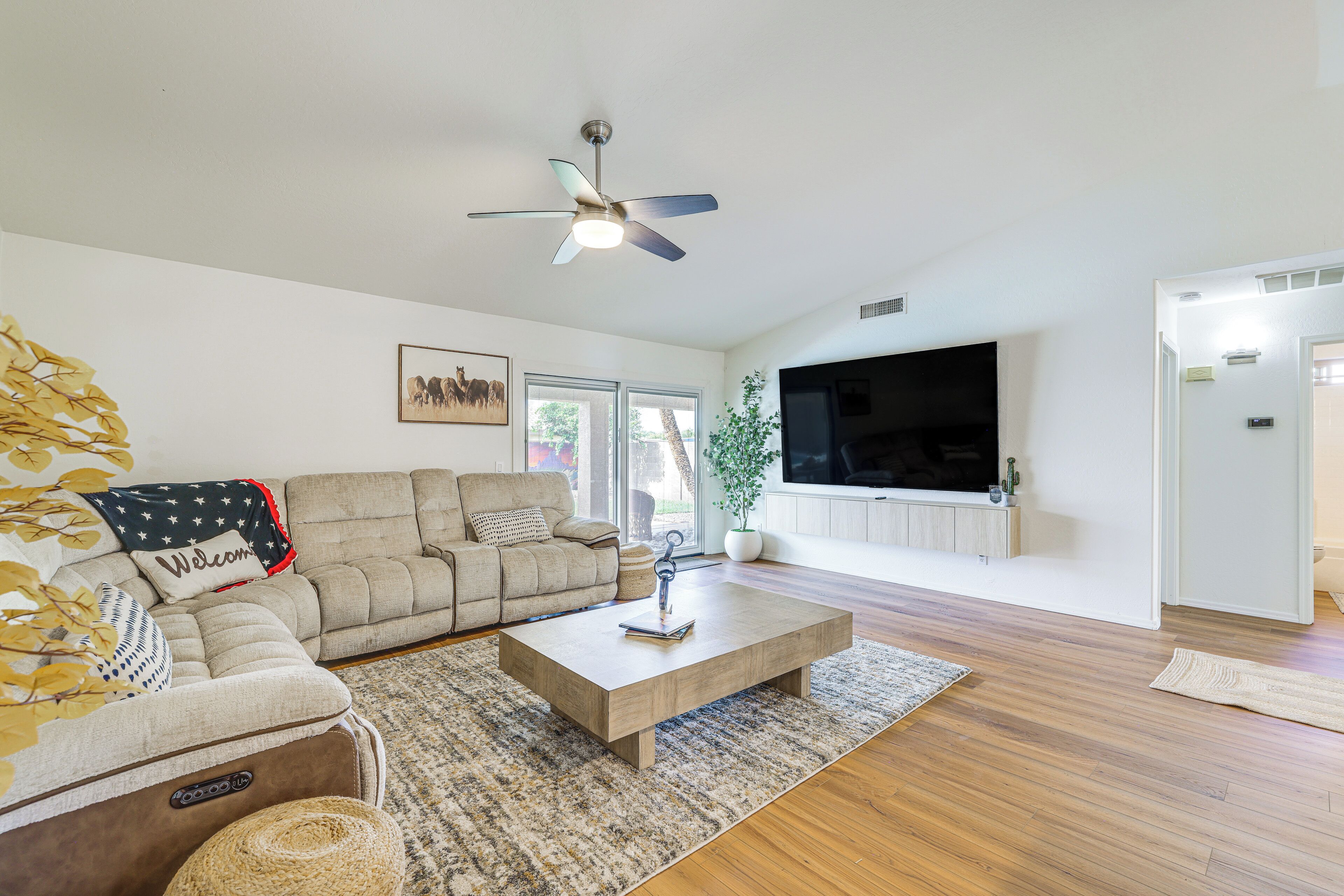 A modern living room with a sofa, coffee table, and a flat-screen TV mounted on the wall.