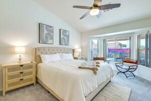 A bedroom with a large bed, a ceiling fan, and artwork on the wall.