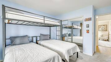 A room with bunk beds, a mirror, and a door leading to another room.