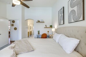 Ein Schlafzimmer mit einem Bett, einem Schreibtisch und einem Stuhl. Es gibt Wanddekorationen und einen Deckenventilator.
