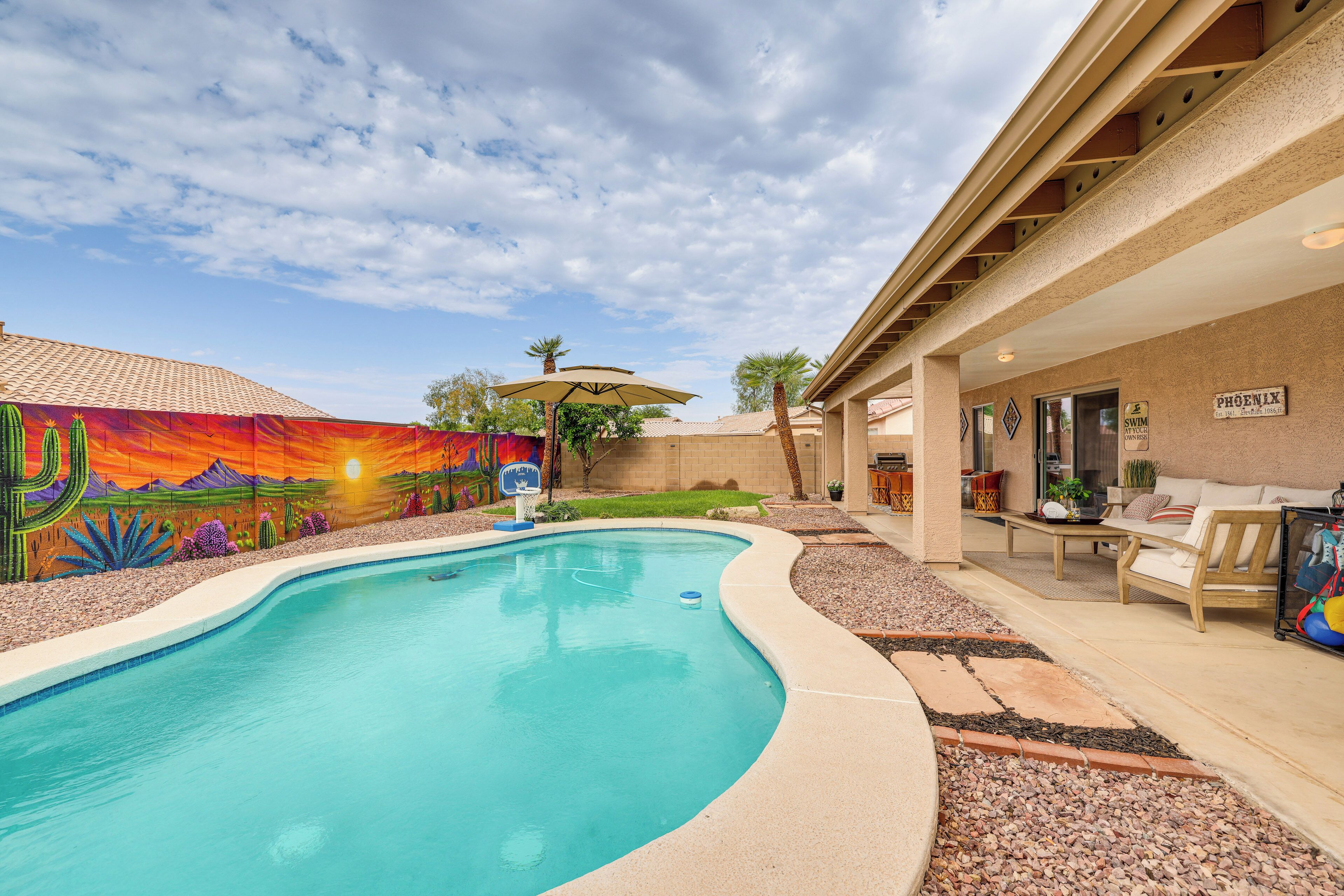 A swimming pool with a mural, a covered patio, and a sign indicating a swimming area.