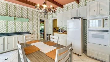 A kitchen with white cabinets, a central island, a chandelier, and a refrigerator.