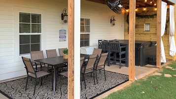 A covered patio with a dining table and chairs, a grill, and a small garden area.