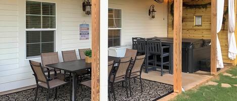 Un patio cubierto con mesa y sillas para comer, una parrilla y un pequeño jardín.