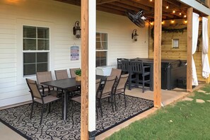 A covered patio with a dining table and chairs, a grill, and a small garden area.