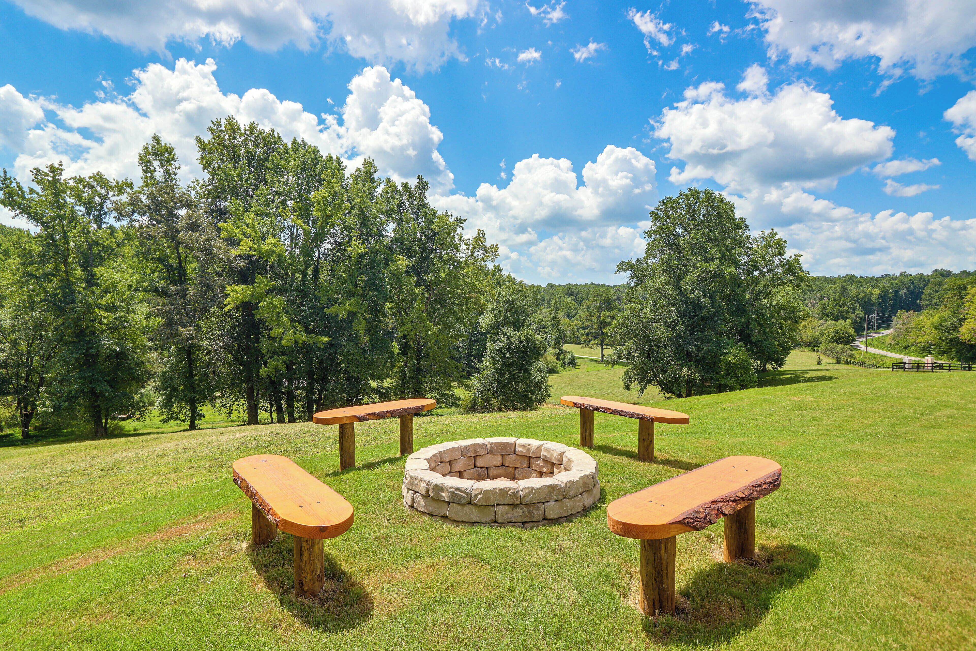 A picnic area with a stone fire pit and wooden benches.
