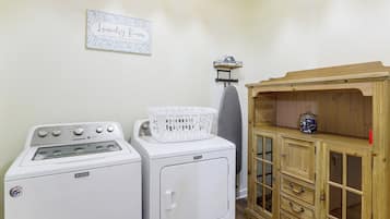 A laundry room with a washing machine, dryer, and a wooden cabinet with drawers.