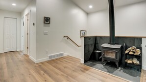 Um quarto com lareira, piso de madeira, porta branca e escada.