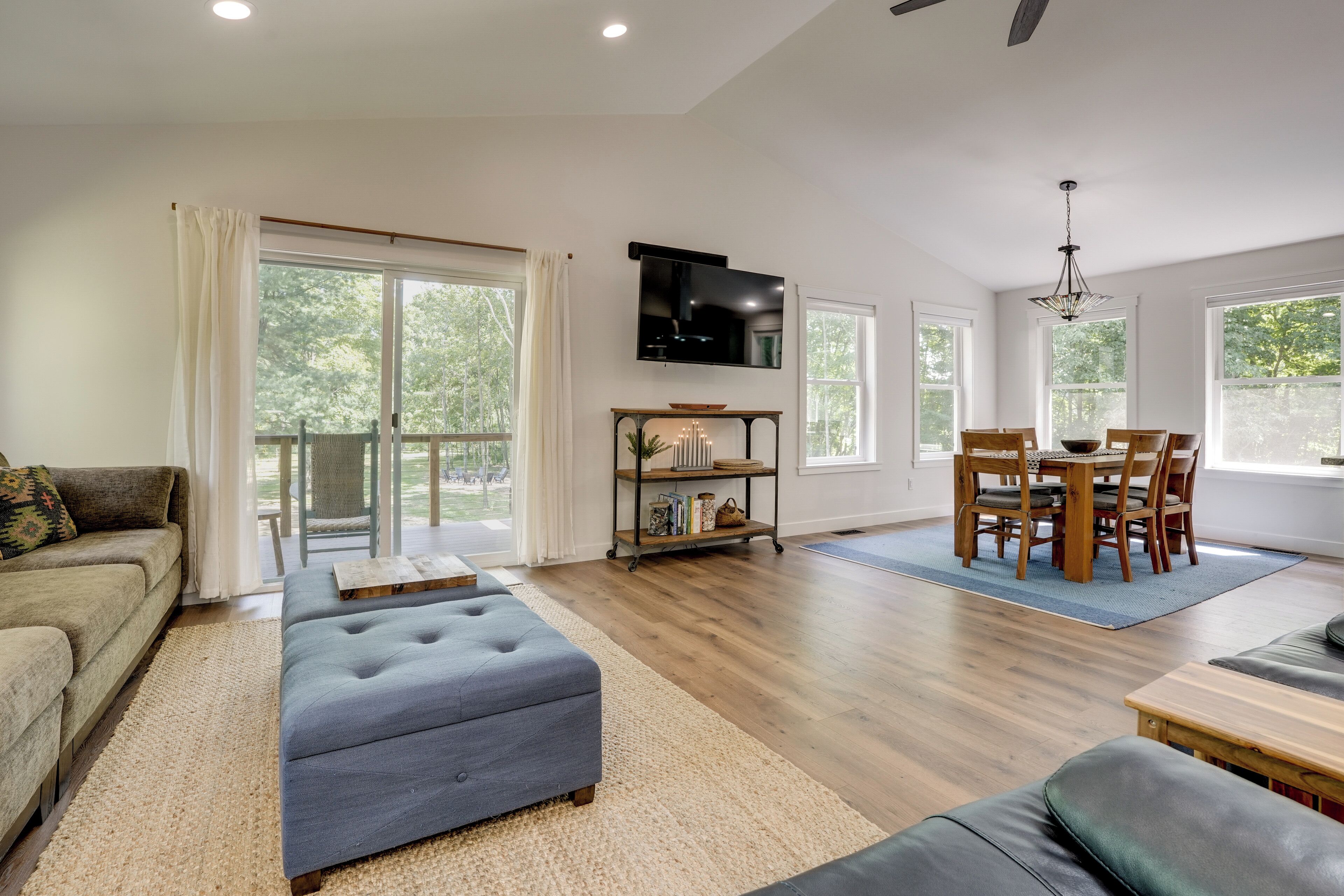 A spacious living room with a sofa, ottoman, and dining area with chairs and a table.