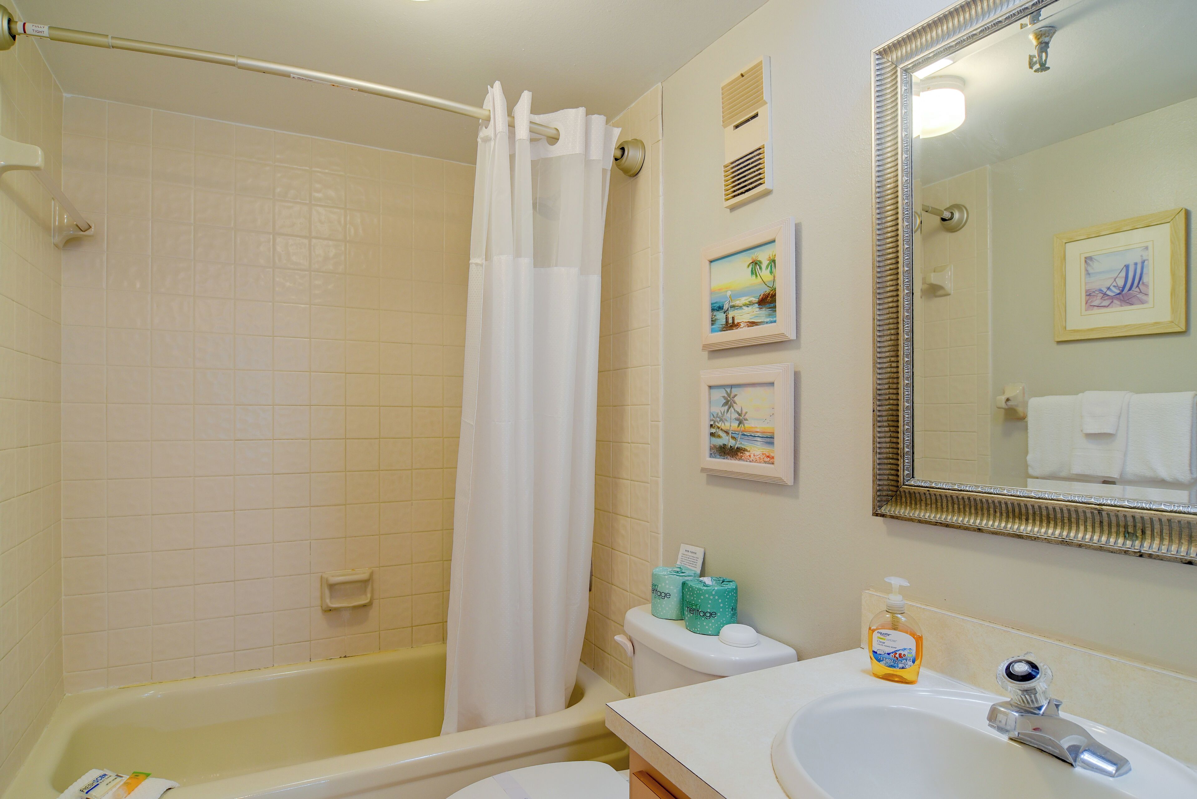 Une salle de bain équipée d’une baignoire, de toilettes, d’un lavabo et d’un rideau de douche.