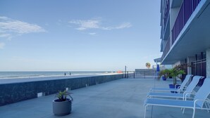 A balcony with a view of the beach, lounge chairs, and potted plants. - Unit w/ Stunning Gulf Views! Steps to Pool & Beach (Madeira Beach)