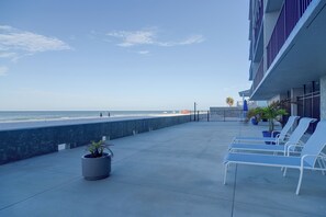 A balcony with a view of the beach, lounge chairs, and potted plants. - Unit w/ Stunning Gulf Views! Steps to Pool & Beach (Madeira Beach)