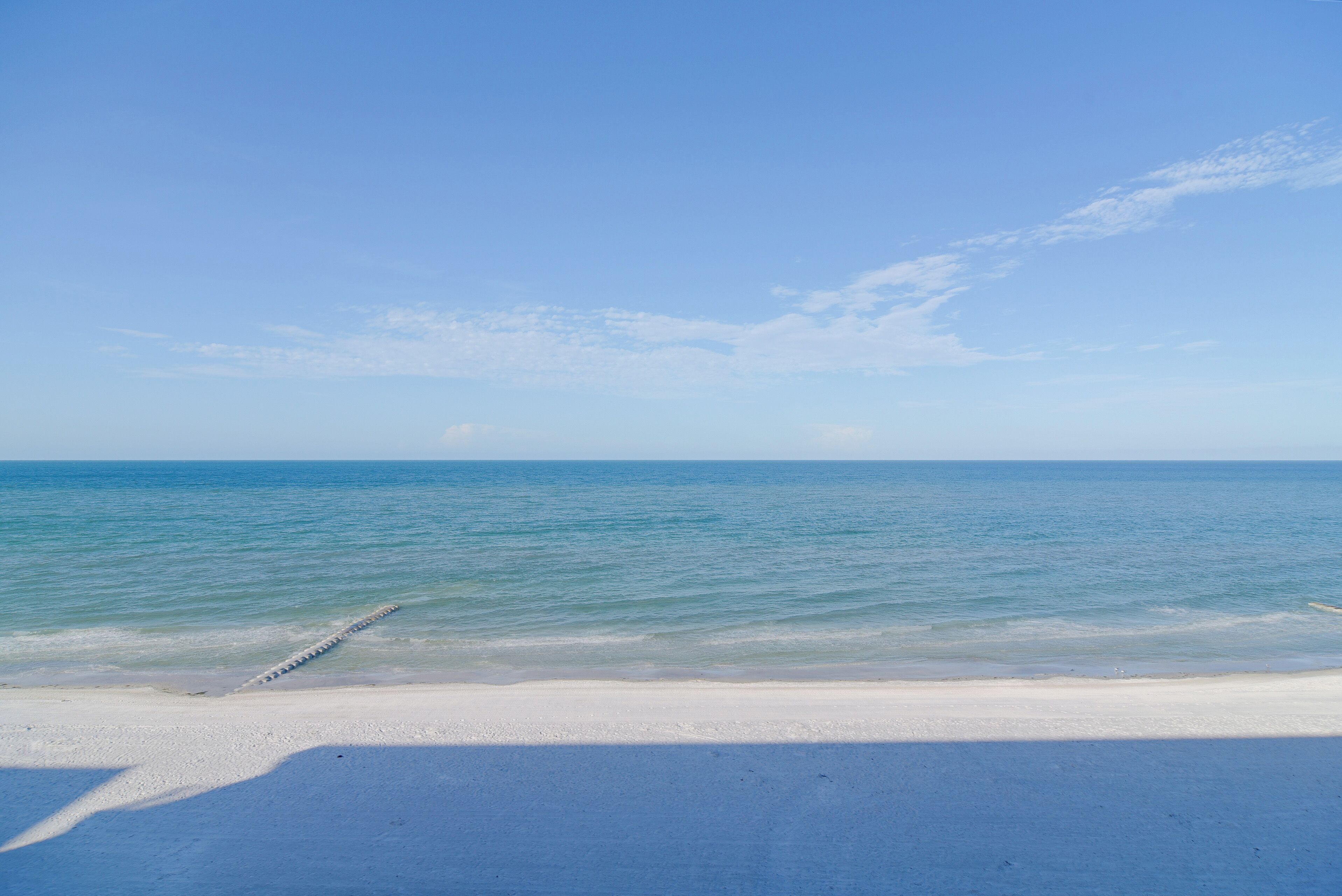 Una playa con cielo despejado y mar tranquilo.