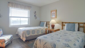 A room with two beds, a window with blinds, a bedside table with a lamp, and a wall decoration. - Unit w/ Stunning Gulf Views! Steps to Pool & Beach (Madeira Beach)