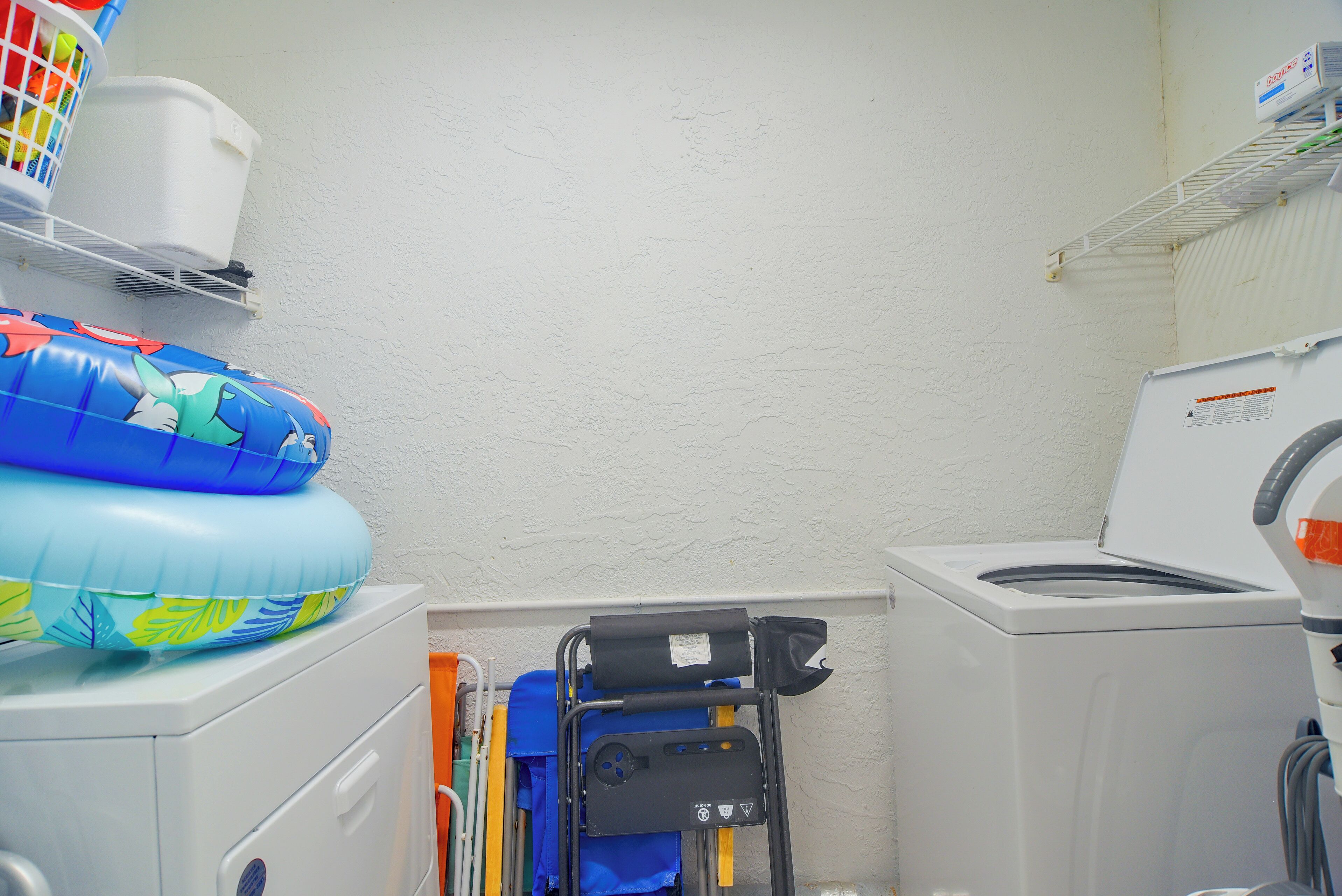 A laundry area with a washing machine, a dryer, and a small shelf with a basket.
