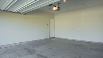 A spacious, empty room with a concrete floor, white walls, and a door.
