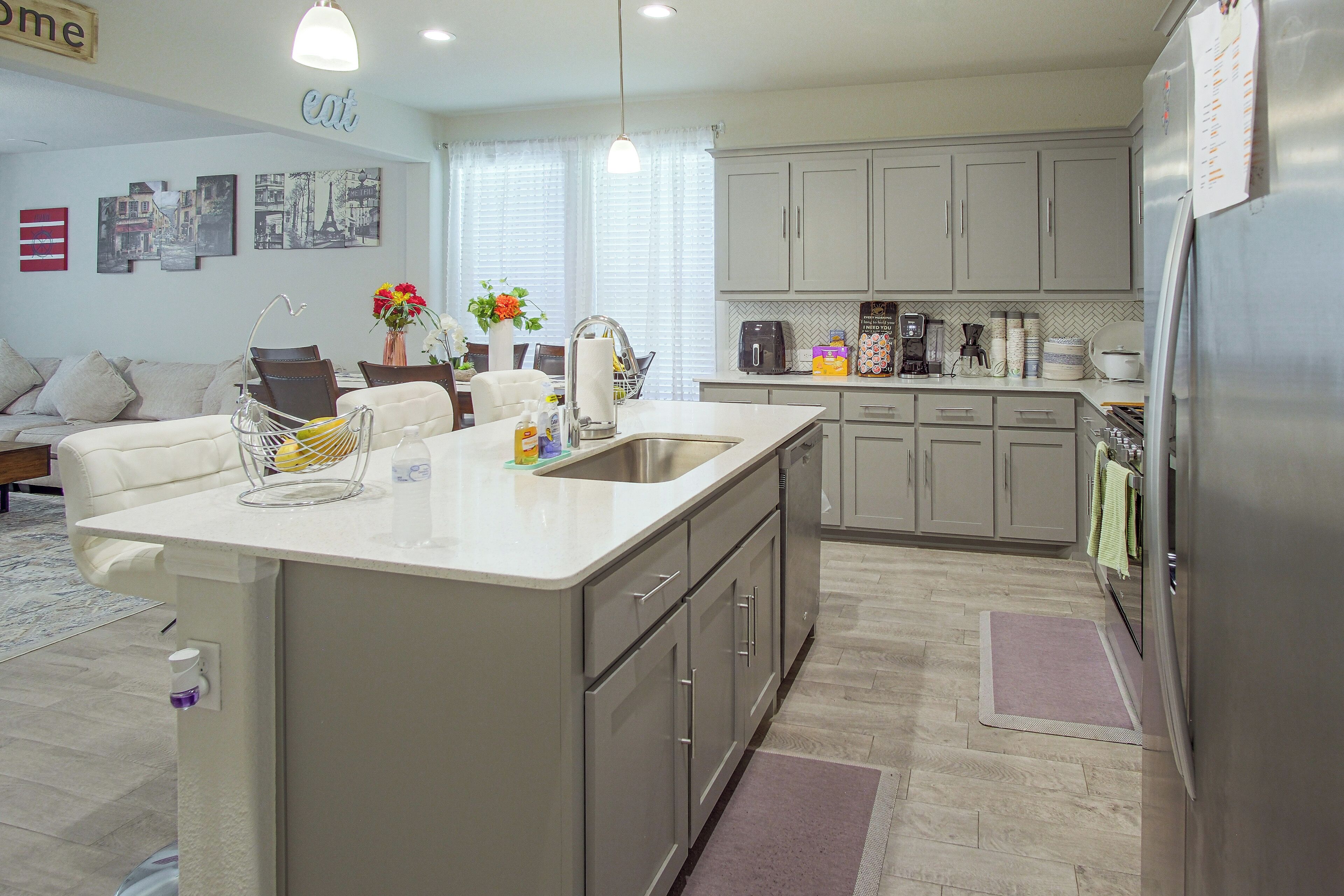 Una cocina moderna con una isla central, electrodomésticos de acero inoxidable y una zona de comedor con sofá y sillas.