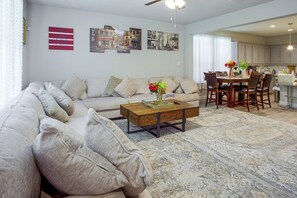 A living room with a sofa, coffee table, and a dining area with chairs and a table. - Family Home 7 Mi to University of North Texas! (Krum)
