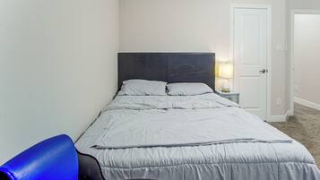 A bedroom with a bed, a nightstand with a lamp, and a chair.