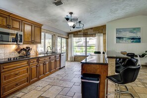 A kitchen with wooden cabinets, a stainless steel microwave, and a large window. - 2 Mi to Six Mile Preserve! Family Getaway w/ Pool (Fort Myers)
