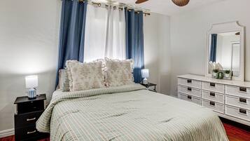 A bedroom with a bed, a nightstand, a dresser, a mirror, and a ceiling fan.