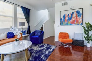 A modern living room with a sofa, armchairs, a coffee table, and a staircase. - Walk to Train Station & More! Modern Compton Unit (Compton)