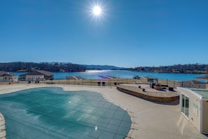 A swimming pool with a glass enclosure, a waterfront view, and a small building with a sign. - Top-floor SML Studio With Lake & Pool Access (Huddleston)