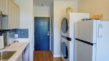 A compact kitchen with a washing machine, a refrigerator, and a sink.