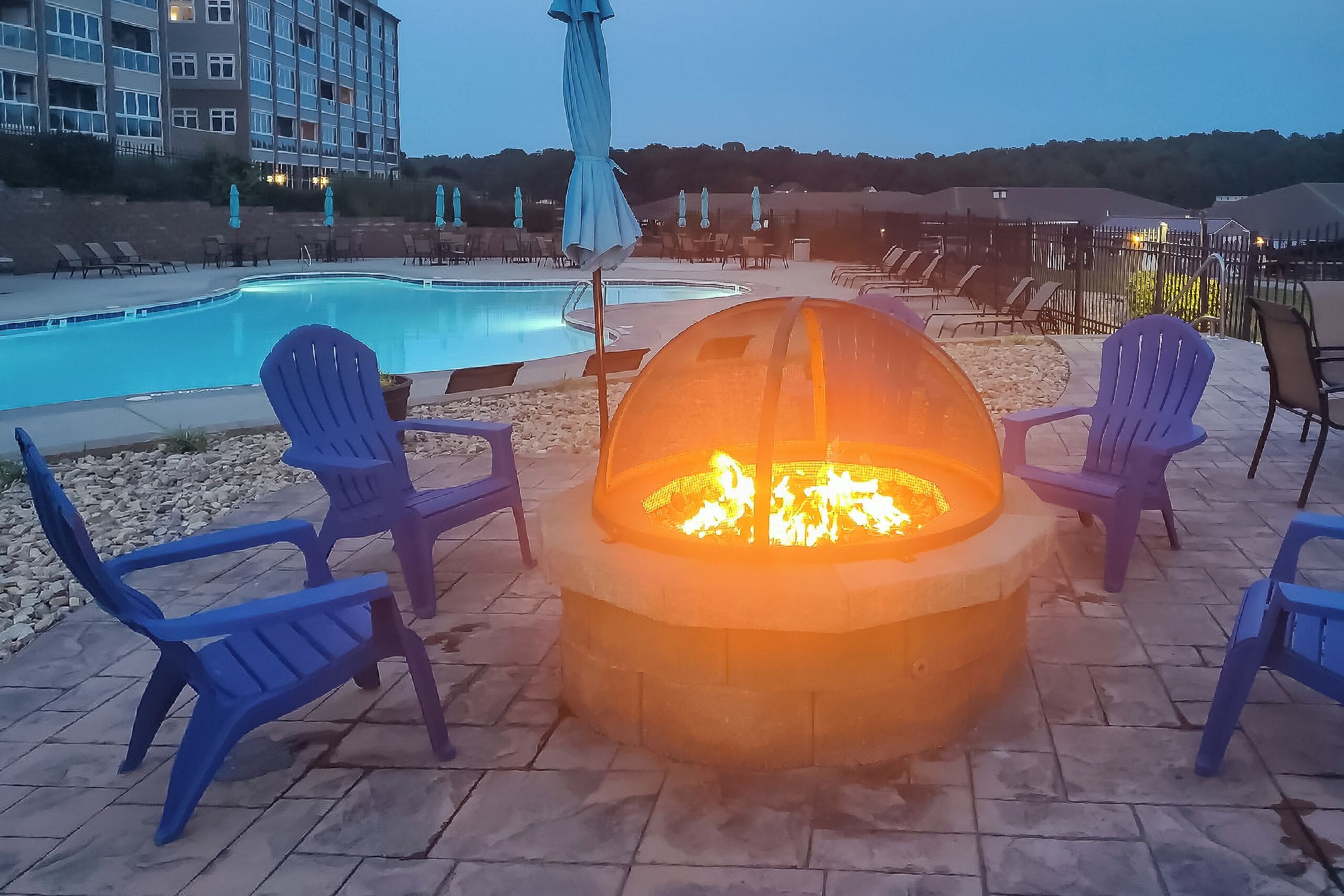 A poolside area with a fire pit and lounge chairs.