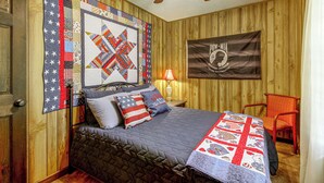 A bedroom with a bed, pillows, a quilt, a flag, a ceiling fan, and a chair. - Centrally Located Nature Escape in Trenton (Trenton)