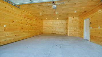 A spacious room with wooden walls and a concrete floor, featuring a door and a ceiling-mounted light fixture.