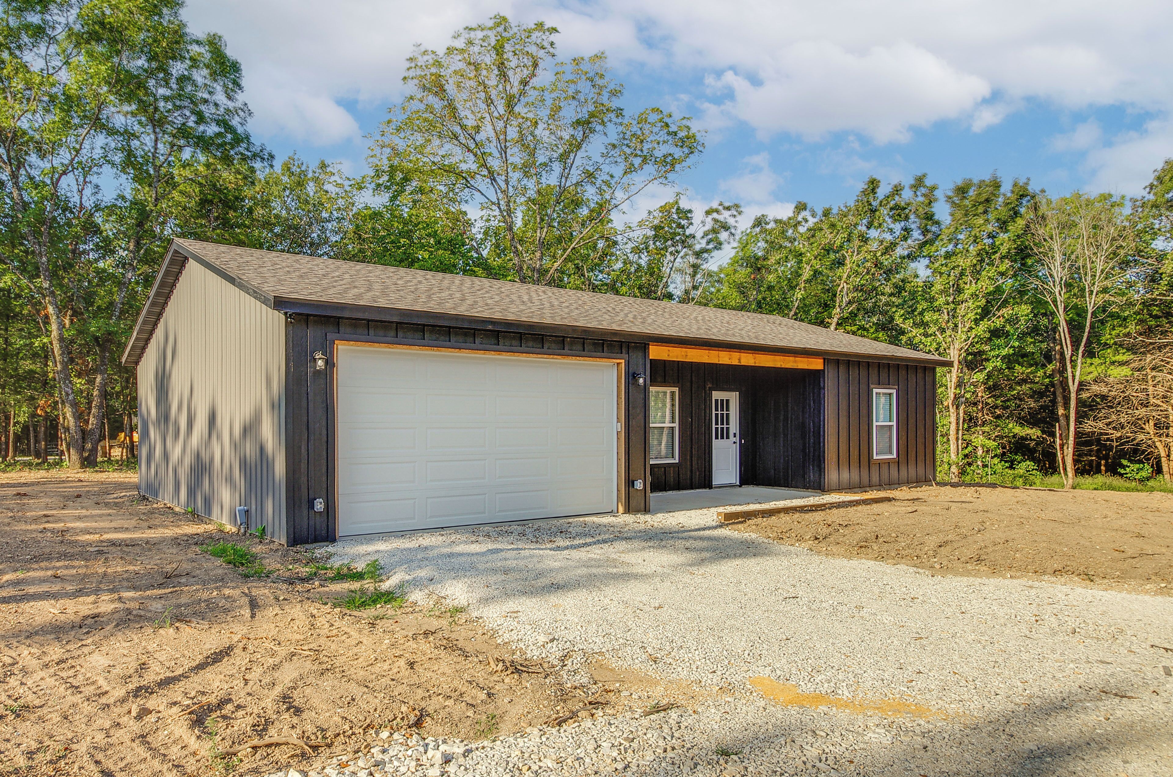 A single-story building with a garage, a covered porch, and a gravel driveway.