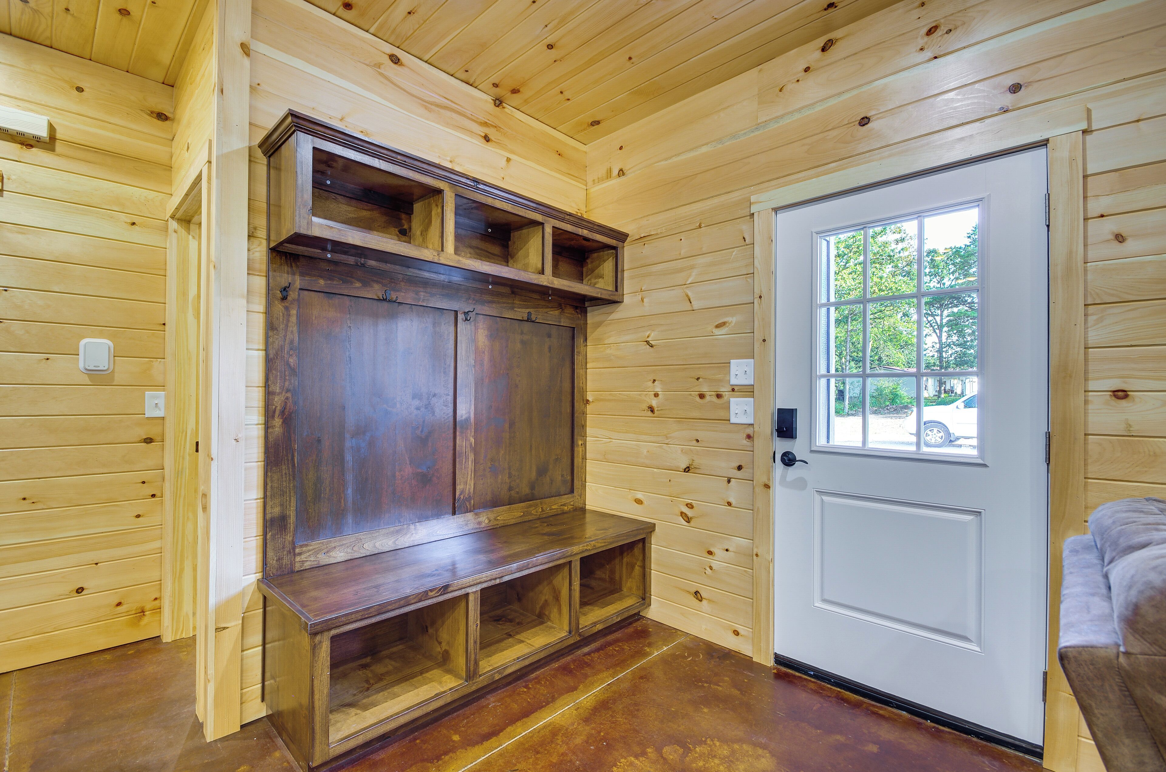 A wooden interior with a door, a bench, and a built-in cabinet.