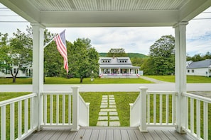 Eine überdachte Veranda mit Blick auf ein Haus und eine Flagge.