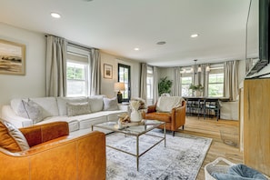 A modern living room with a sofa, coffee table, and a dining area with chairs and a table. - Modern Farmhouse Between Mount Snow & Stratton! (Wardsboro)